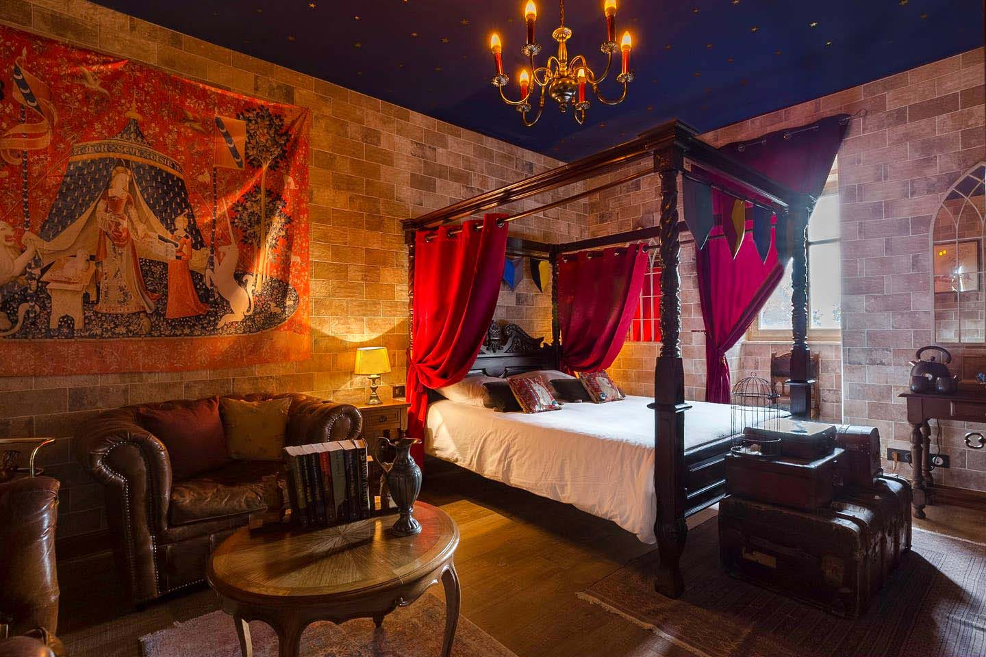 Chambre à coucher du gite du sorcier à Colmar - Lit à baldaquin ancien en bois, lustre avec bougies, mur en pierre